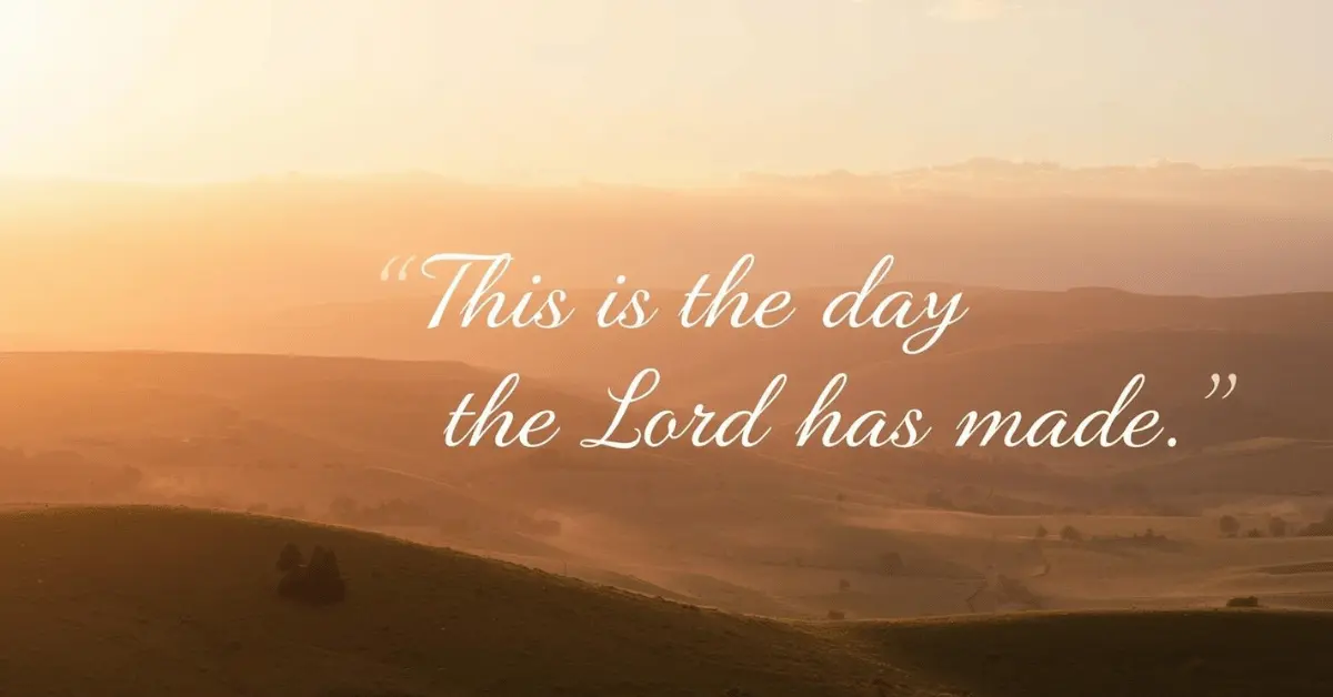 Sunrise shining over green hills with the words “This is the day the Lord has made” written across the sky